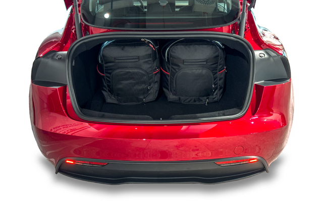 Coffre ouvert d'une voiture rouge avec deux sacs à dos noirs