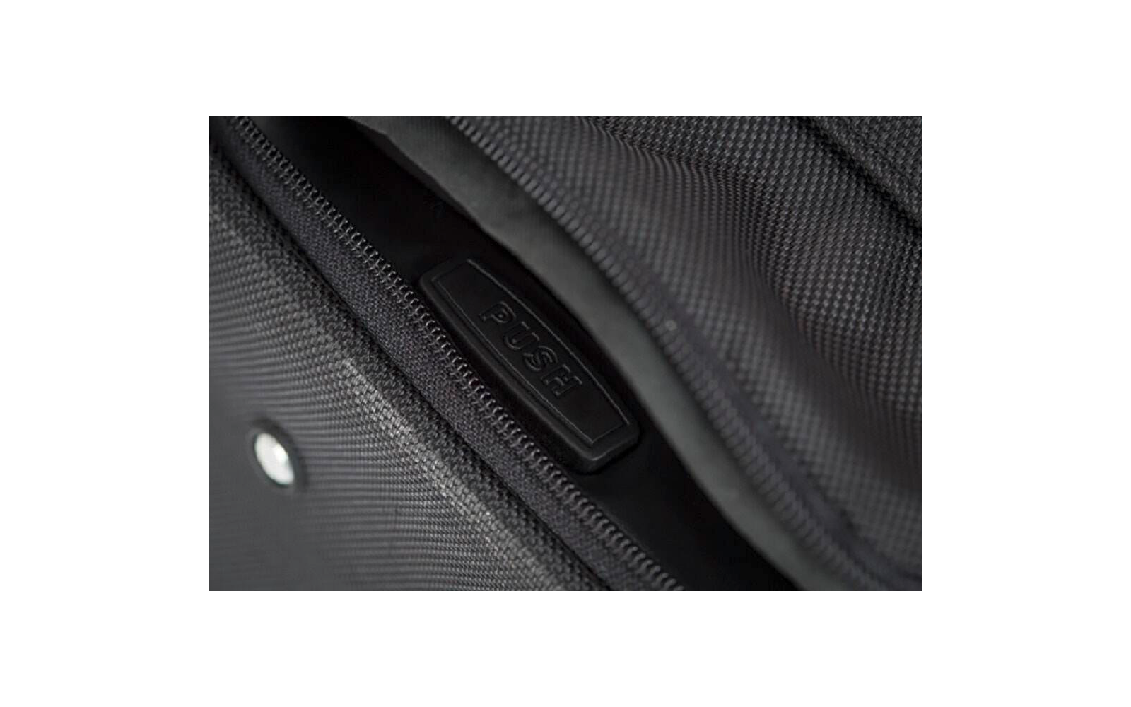 Gros plan d'une fermeture éclair noire sur un sac, partiellement ouverte, avec une tirette en plastique noir portant l'inscription 'PUSH' et tissu texturé
