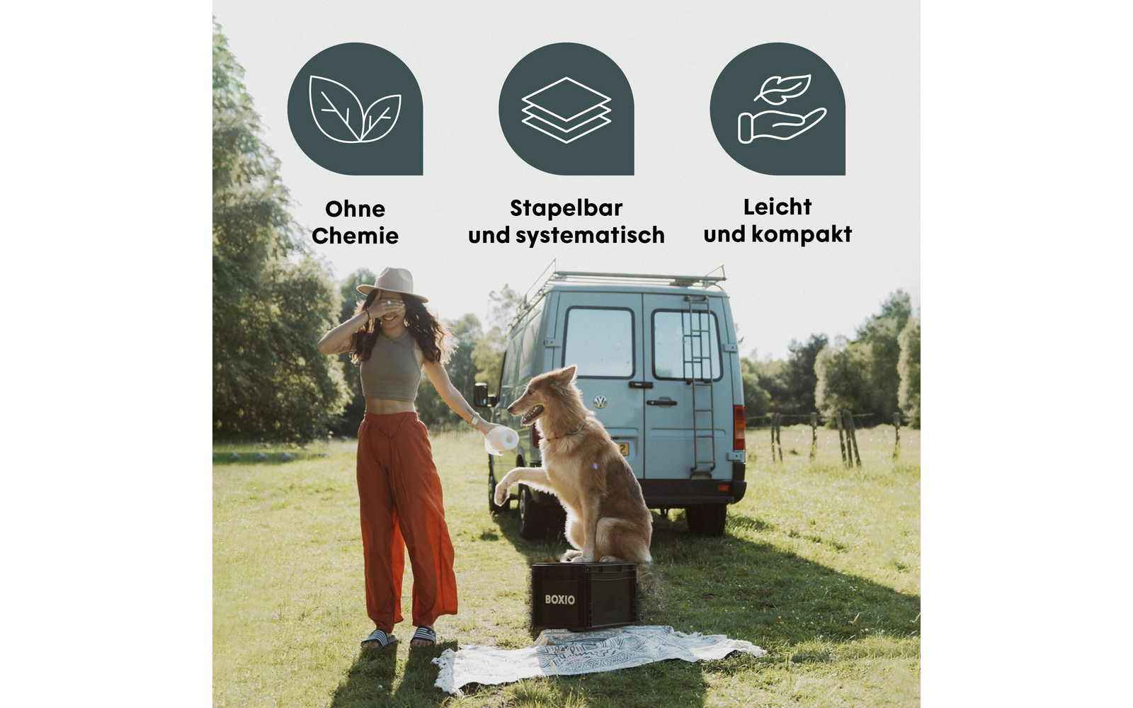Frau mit Hut und roten Hosen steht neben Hund, der auf einer schwarzen Box vor einem hellblauen Campingbus sitzt; darüber drei runde Icons mit Blattsymbolen und den Texten "Ohne Chemie", "Stapelbar und systematisch", "Leicht und kompakt"; Picknickdec