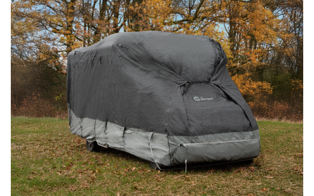 Large rectangular object on wheels fully covered by a gray protective cover; wheels and bottom edge visible