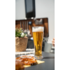 Een glas bier op een tafel met een bord eten ernaast