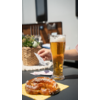 Een glas bier en een belegde sandwich op een houten tafel buiten