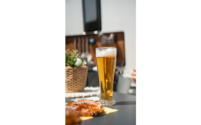 Ein Glas Bier auf einem Tisch mit einem Teller Essen daneben