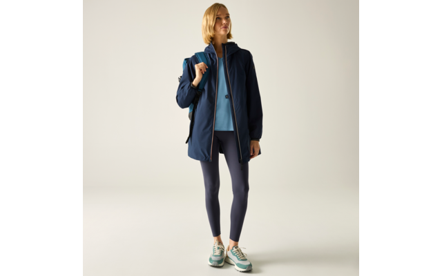 Person steht vor hellem Hintergrund, trägt dunkle Jacke, hellblauen Pullover, dunkelblaue Leggings, Sneaker und Rucksack