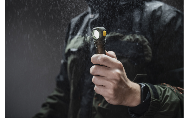 Hand hält eine Taschenlampe bei Regen