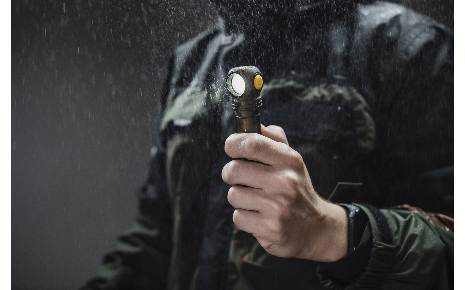 Hand hält eine Taschenlampe bei Regen