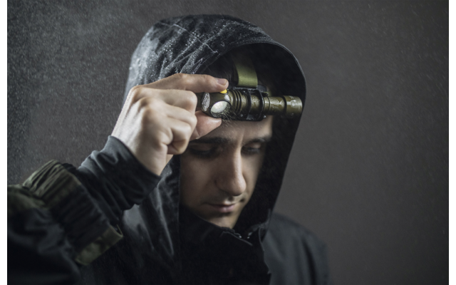 Porträt eines Mannes mit Kapuzenpullover, der eine Taschenlampe an die Stirn hält