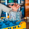 Hand hält ein Glas unter einen Wasserauslauf in einer Bar