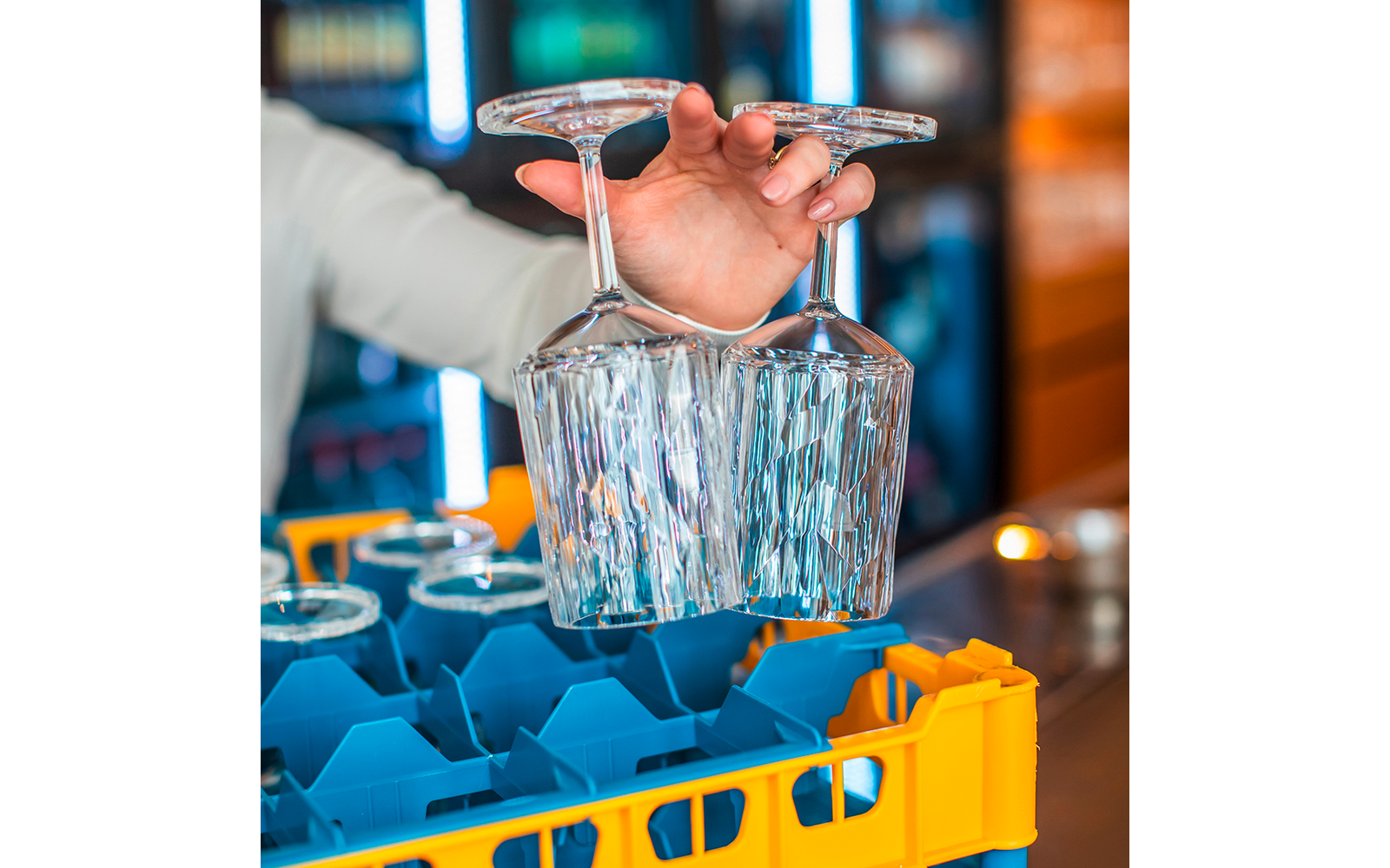 Hand hält ein Glas unter einen Wasserauslauf in einer Bar