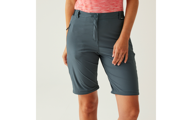 Taille bis Mitte Oberschenkel einer Person in dunkelgrauen knielangen Shorts und rosa meliertem Oberteil, Hände an den Seiten, rechte Hand auf dem rechten Oberschenkel