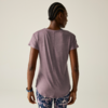 Person von hinten in violettem T-Shirt, gemusterten Leggings und Sportarmband vor hellem Hintergrund