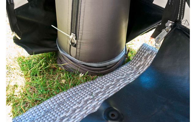 Unterer Bereich eines aufrechten schwarzen Zylinders mit Reißverschluss, befestigten Gurten und grauem, gewebtem Gurt auf Gras