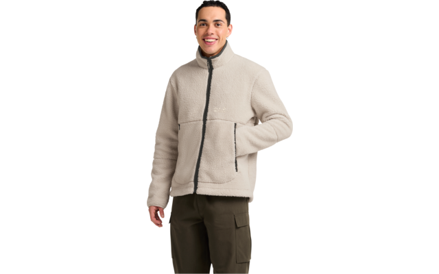 Person mit kurzem dunklem Haar, lächelnd, trägt helle Fleecejacke mit Reißverschluss und seitlichen Taschen, eine Hand in der Tasche