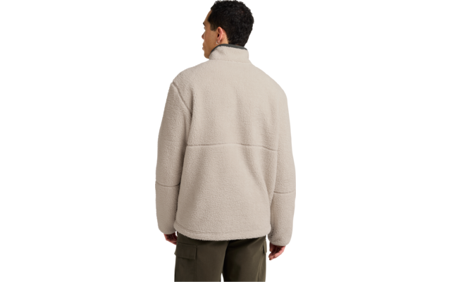 Rückansicht einer Person mit kurzem dunklem Haar, trägt eine beige Fleecejacke und olivgrüne Hosen