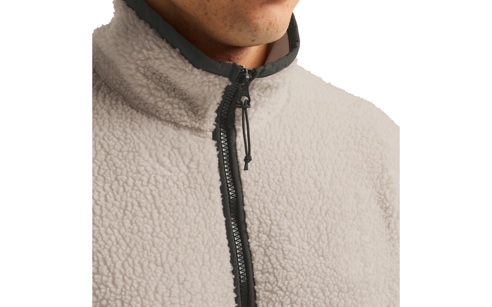 Nahaufnahme von Kinn, Hals und Oberkörper in einer beigen Teddy-Fleecejacke mit schwarzem Reißverschluss und Kordel