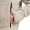 Hand in Reißverschlusstasche einer hellbeigen Fleecejacke