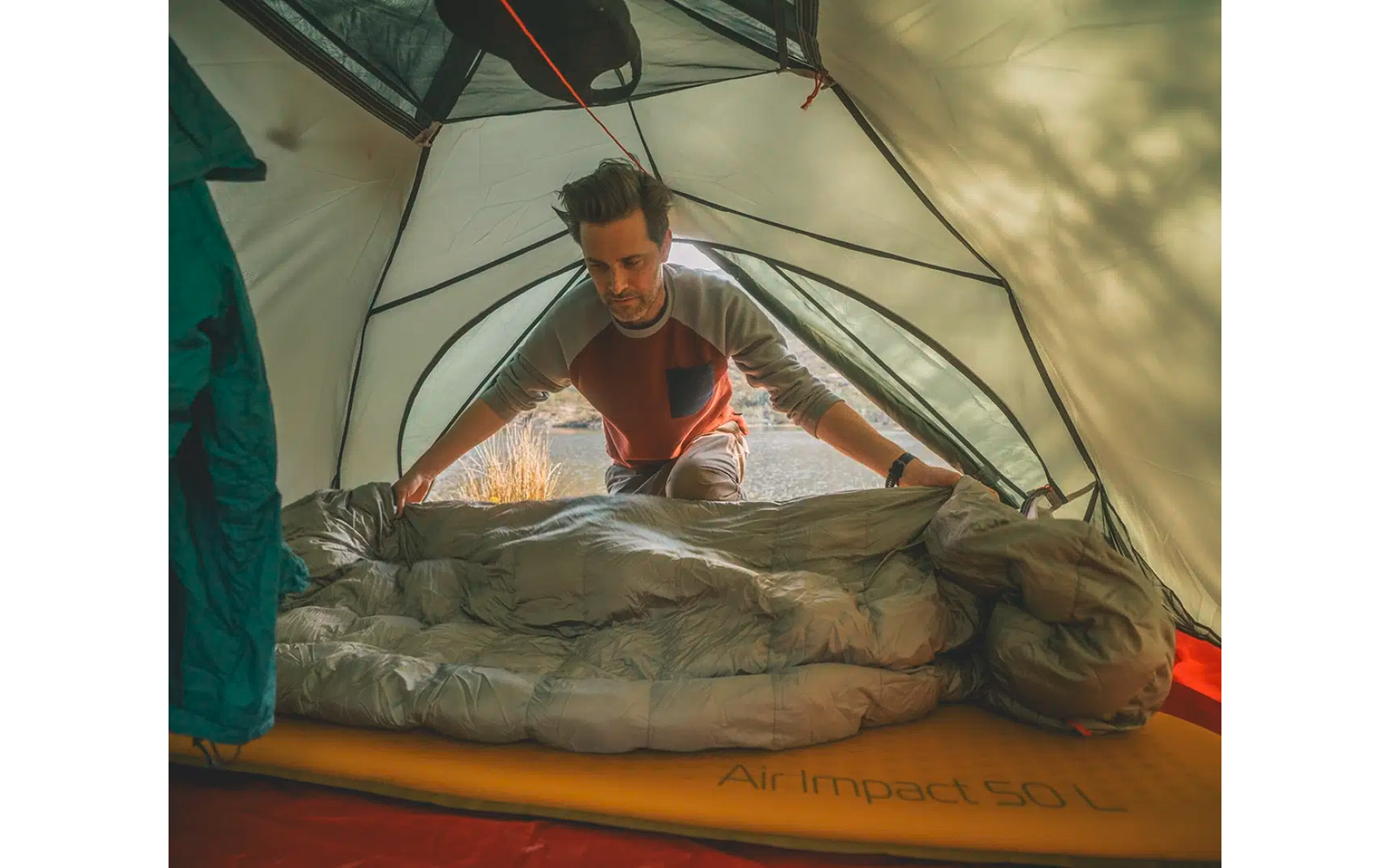 Person liegt in einem Schlafsack im Zelt und schaut heraus
