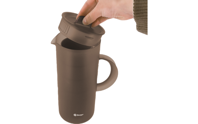 Main avec une manche brune soulève le couvercle amovible d'une tasse brun foncé avec anse ; logo blanc 'Berger' en bas