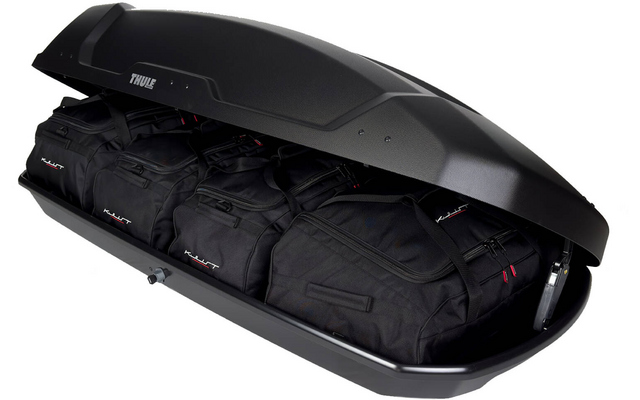 Geöffnete schwarze Dachbox mit mehreren schwarzen Reisetaschen im Innenraum