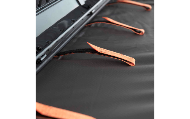 Schwarze strukturierte Oberfläche mit mehreren orangefarbenen Stoffschlaufen und einer Metallleiste am oberen Bildrand