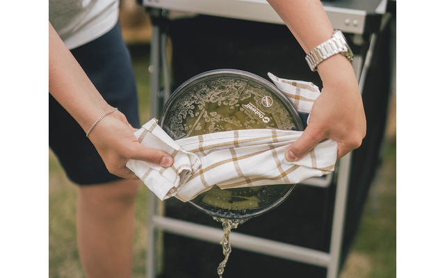 Twee handen houden een ronde metalen frame met witte en groene elementen