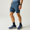 Unterkörper einer Person mit blauen Shorts, dunklen Socken, blauen Sportschuhen mit weißer Sohle und Smartwatch am linken Handgelenk auf hellem Hintergrund