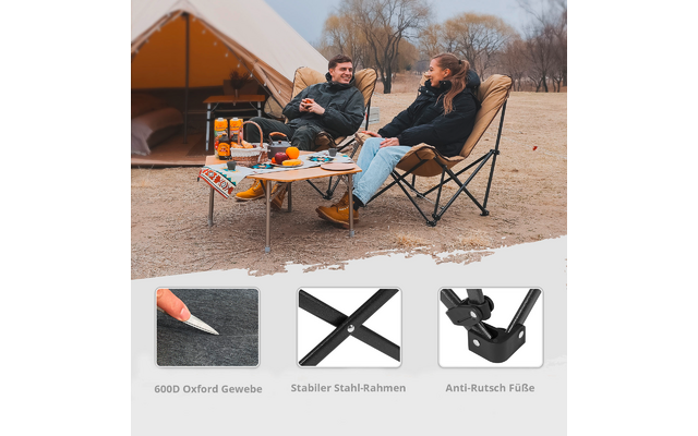 Zwei Personen sitzen entspannt auf Klappstühlen vor einem Zelt, auf einem Holztisch stehen Campingausrüstung und Getränke