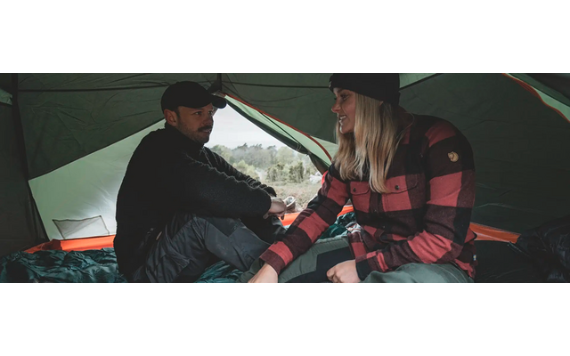 Zwei Personen sitzen im Zelt und halten sich an den Händen