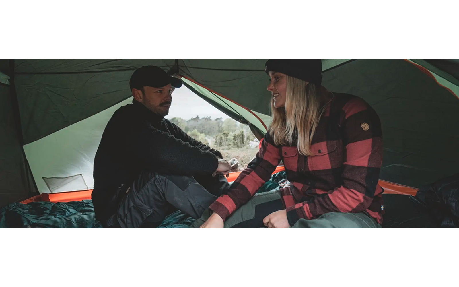 Zwei Personen sitzen im Zelt und halten sich an den Händen