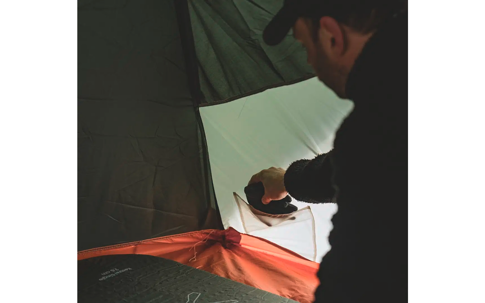 Person gießt Wasser aus einer Kanne in einen Becher in einem Zelt