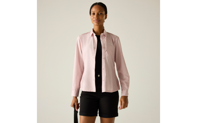 Person steht frontal vor hellem Hintergrund, trägt hellrosa langärmeliges Hemd offen über schwarzem Oberteil, schwarze Shorts, hält schwarzen Riemen in linker Hand