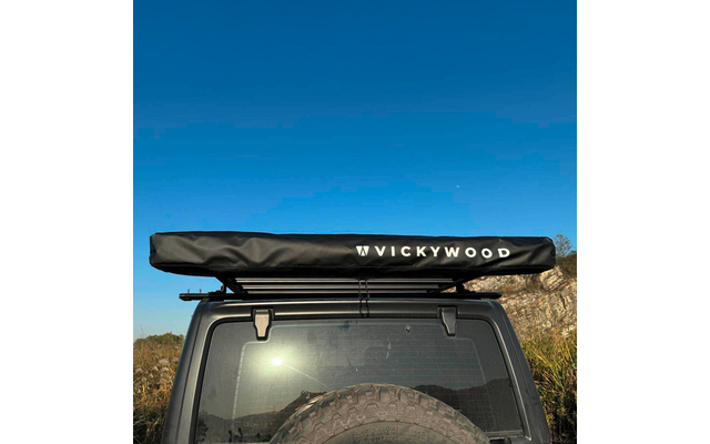 Heck eines Geländewagens mit Dachträger und schwarzer, zusammengefalteter Plane mit Schriftzug "VICKYWOOD", sichtbares Ersatzrad, blauer Himmel und felsige Vegetation im Hintergrund