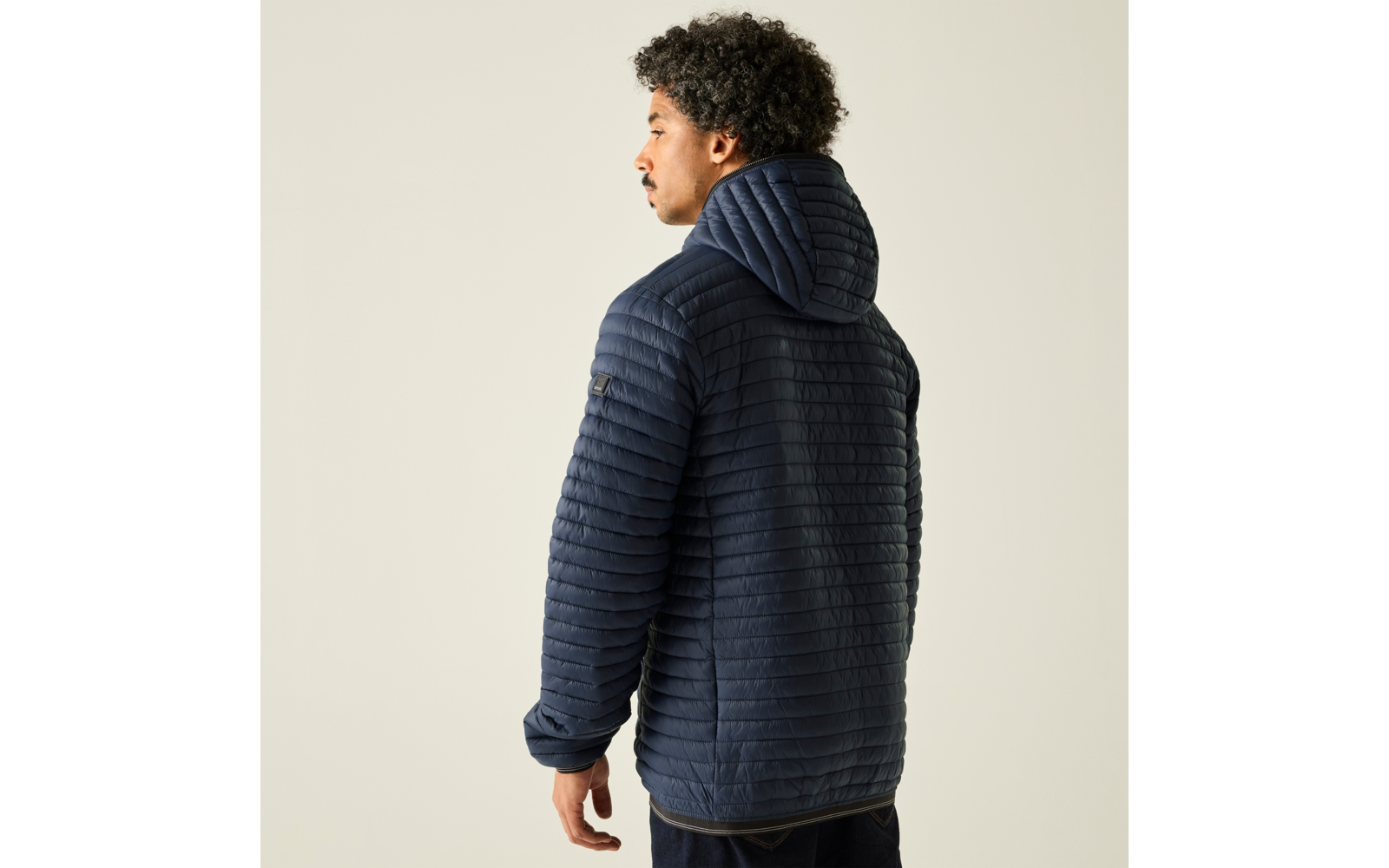 Person von hinten, leicht zur Seite gedreht, trägt dunkelblaue gesteppte Kapuzenjacke