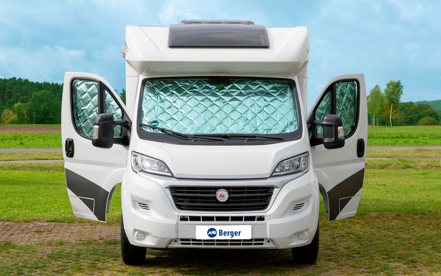 Weißes Wohnmobil mit geöffneten Türen steht auf einem Feldweg vor grünem Wald