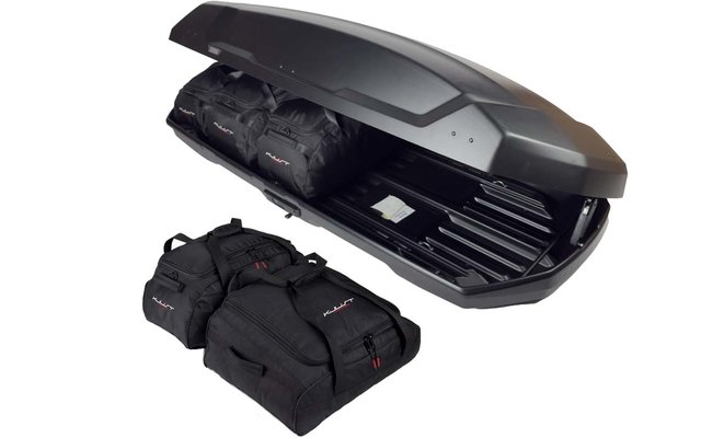 Geöffnete schwarze Dachbox auf weißem Hintergrund, zwei schwarze Reisetaschen im Inneren und zwei schwarze Taschen davor