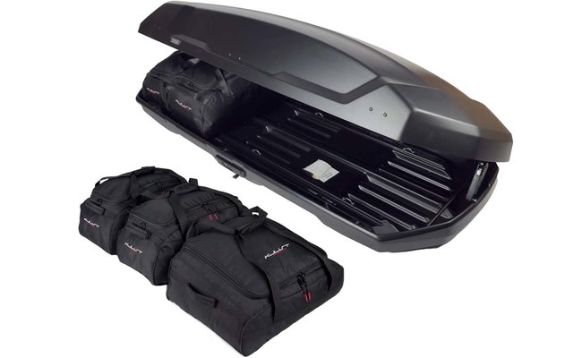 Offene schwarze Dachbox mit vier schwarzen Reisetaschen daneben