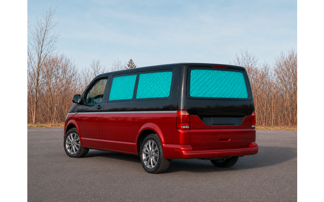 Furgoneta roja, cubiertas acolchadas azules en las ventanas, aparcada en una carretera; árboles sin hojas y cielo al fondo