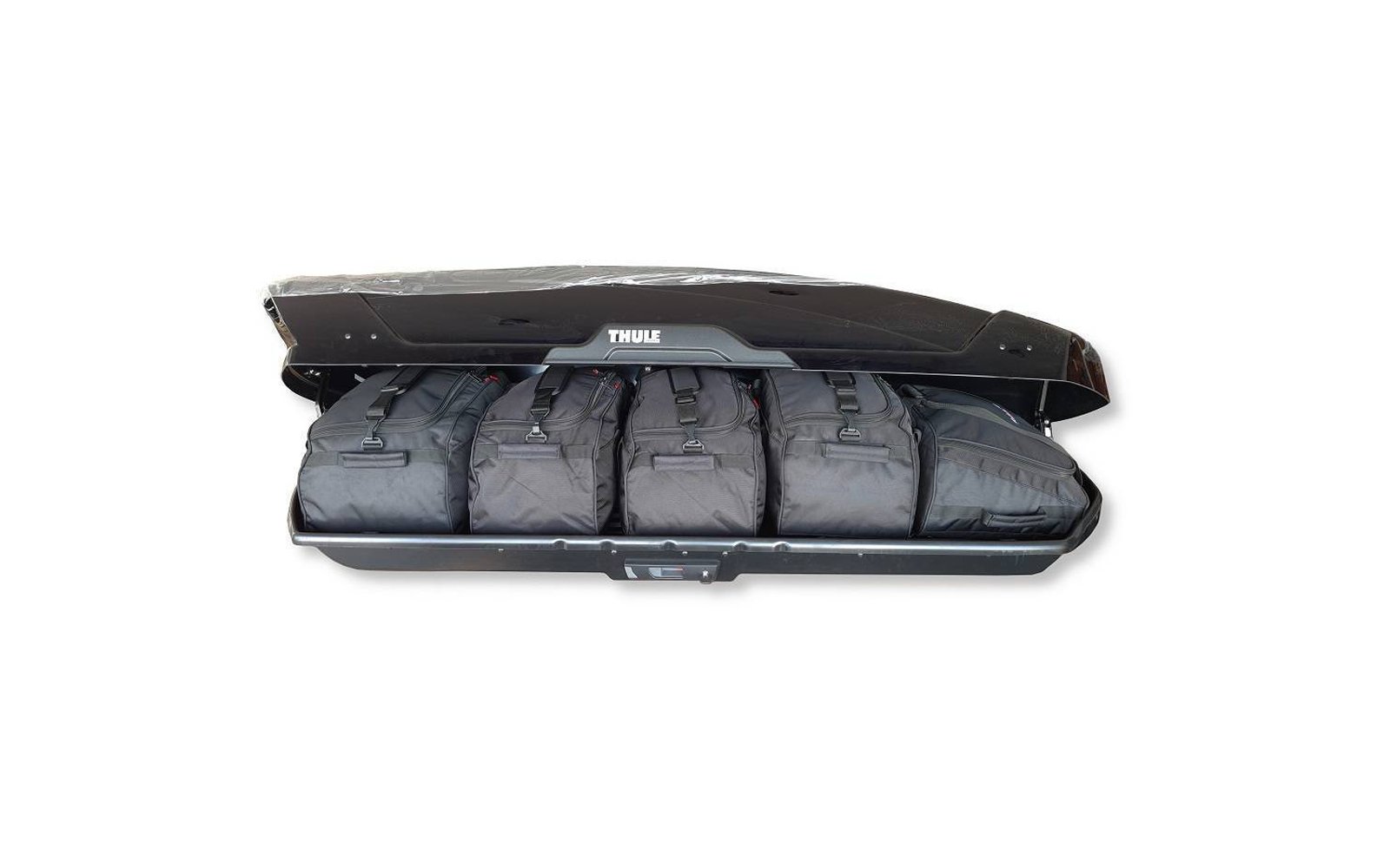 Coffre de toit Thule noir ouvert contenant cinq sacs de voyage noirs côte à côte