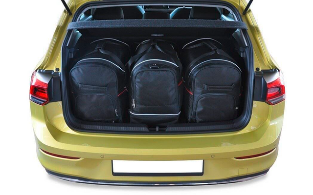 Coffre ouvert d'une voiture jaune contenant trois sacs à dos noirs côte à côte