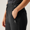 Eine Hand steckt in der Seitentasche einer schwarzen Hose mit Reißverschluss