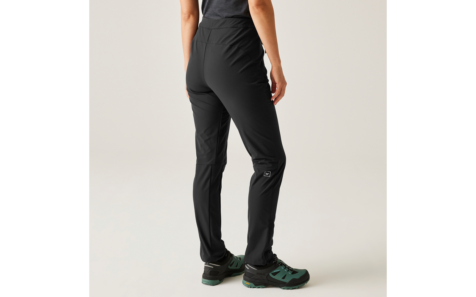 Person trägt schwarze Hose und grüne Schuhe, seitliche Ansicht von der Hüfte bis zu den Füßen