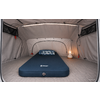 Intérieur d'une tente grise avec un matelas gonflable bleu portant un logo, un oreiller à motif et une lanterne à droite