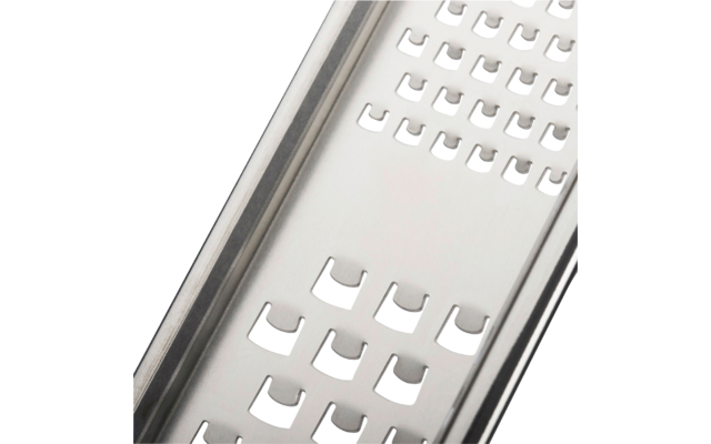 Close-up van een roestvrijstalen raspplaat met rijen rechthoekige, U-vormige openingen