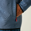 Eine Hand steckt in der Seitentasche einer blauen Jacke