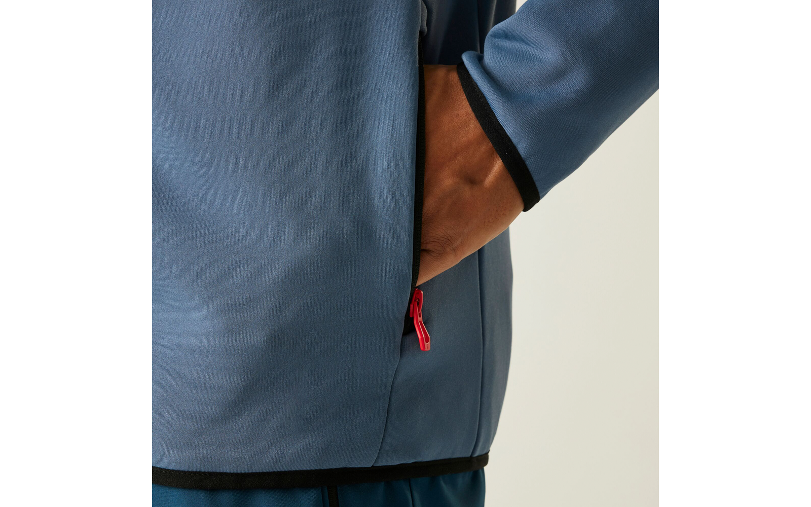Eine Hand steckt in der Seitentasche einer blauen Jacke