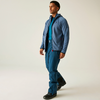 Mann im blauen Hemd, dunkler Jacke und Jeans steht auf hellgrauem Hintergrund