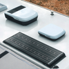 Weiße Dachfläche mit drei weißen, abgerundeten rechteckigen Aufbauten (einer teilweise sichtbar), einem kleinen runden Entlüftungsstutzen und einem schwarzen Solarpanel mit sichtbaren Solarzellen