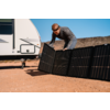 Mann montiert Solarpanels auf Boden vor Wohnmobil