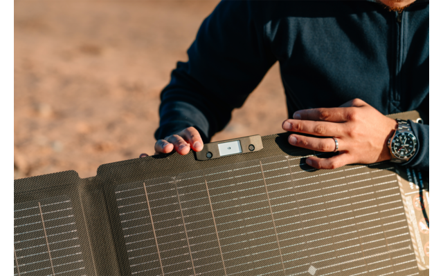 Person hält ein faltbares Solarpanel im Freien