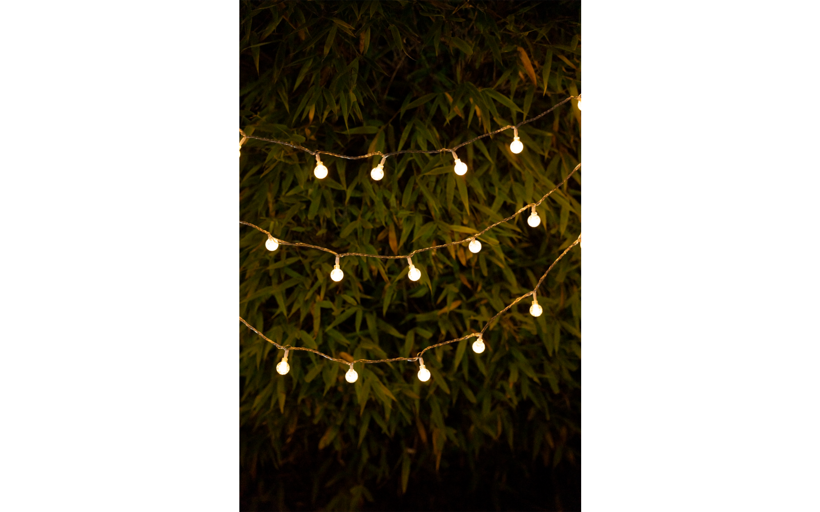 Frau sitzt am Café-Tisch und lächelt, im Hintergrund Blumen und Holztisch